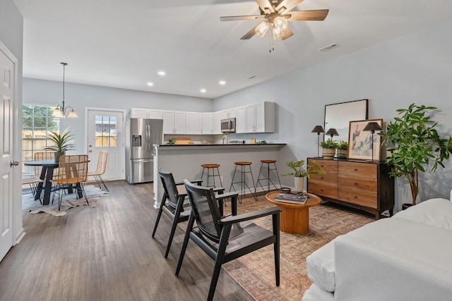 living room featuring ceiling fan with notable chandelier, recessed lighting, wood finished floors, and visible vents