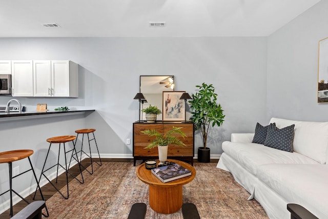 living room featuring wood finished floors, baseboards, and visible vents