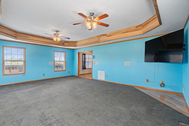 unfurnished living room featuring carpet, a tray ceiling, baseboards, and visible vents