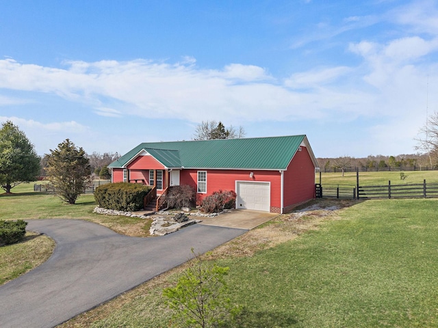 view of front of house featuring a front yard, fence, driveway, an attached garage, and metal roof