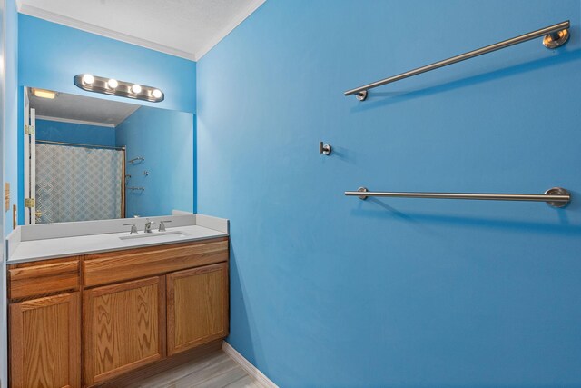 bathroom featuring a shower with curtain, wood finished floors, crown molding, baseboards, and vanity