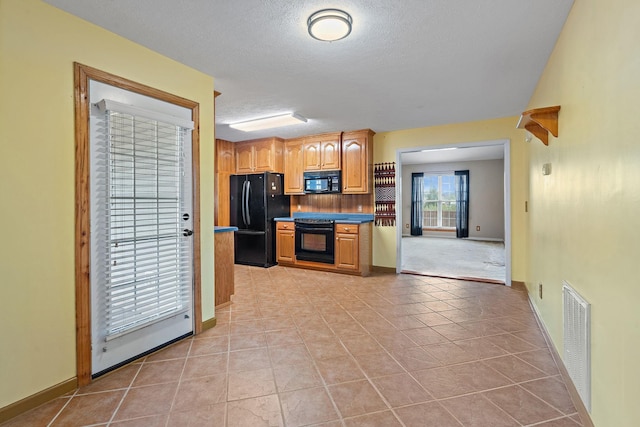 kitchen with tasteful backsplash, visible vents, black appliances, light tile patterned floors, and a textured ceiling