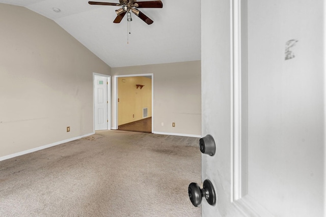 carpeted empty room with vaulted ceiling, a ceiling fan, and baseboards