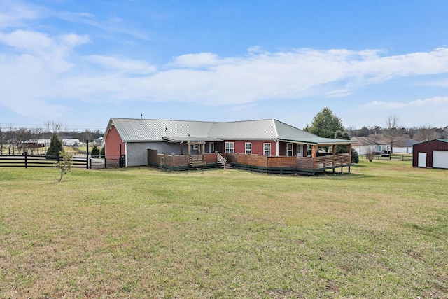 back of property with an outbuilding, fence, a yard, a deck, and metal roof