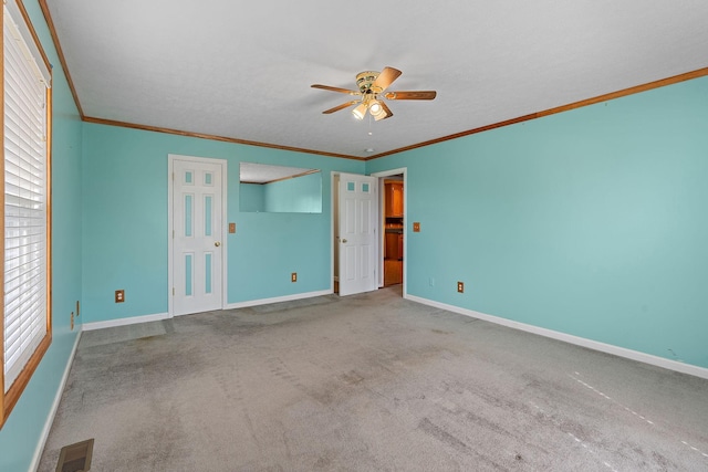 unfurnished bedroom featuring visible vents, baseboards, ornamental molding, and carpet flooring