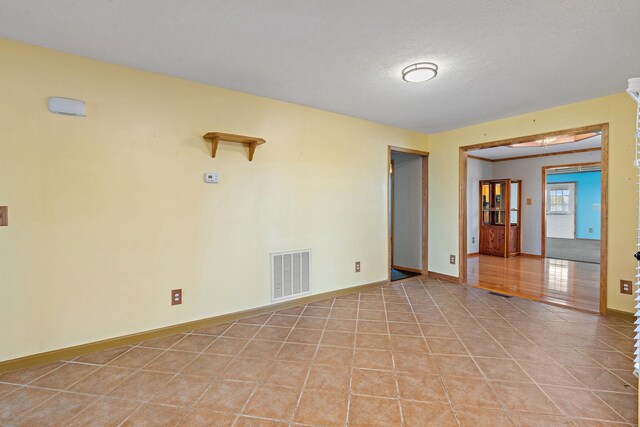 unfurnished room featuring light tile patterned flooring, visible vents, and baseboards