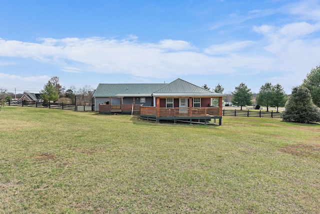 back of property with a lawn, fence, and metal roof