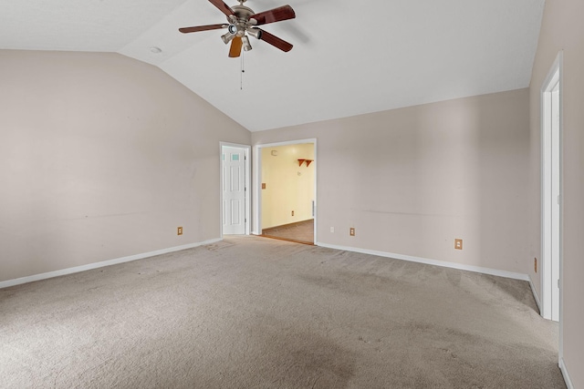 carpeted spare room featuring vaulted ceiling, a ceiling fan, and baseboards