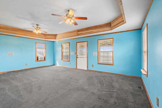 carpeted spare room featuring a raised ceiling, crown molding, a healthy amount of sunlight, and visible vents