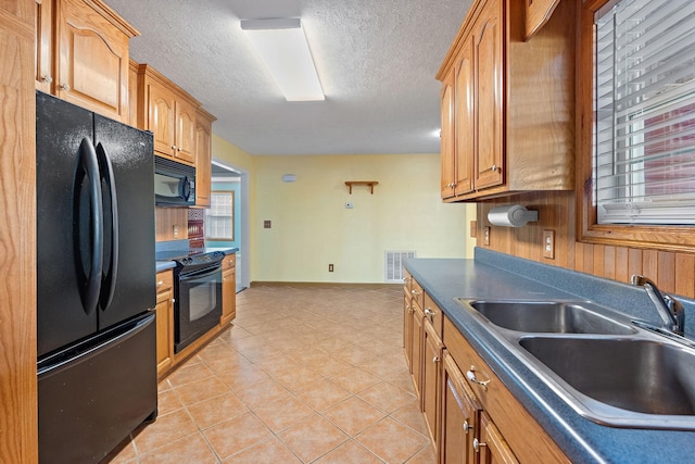 kitchen featuring visible vents, black appliances, a sink, dark countertops, and light tile patterned floors