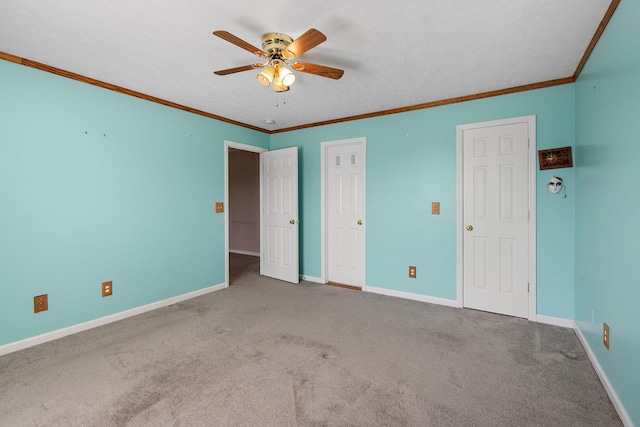 unfurnished bedroom with carpet flooring, baseboards, a ceiling fan, and crown molding