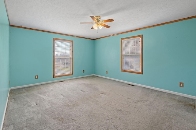 carpeted spare room featuring visible vents, baseboards, ornamental molding, a textured ceiling, and a ceiling fan