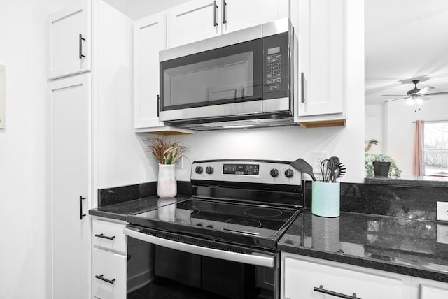 kitchen featuring ceiling fan, dark stone counters, appliances with stainless steel finishes, and white cabinets