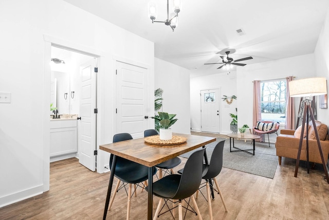 dining space featuring a ceiling fan, baseboards, visible vents, and light wood finished floors