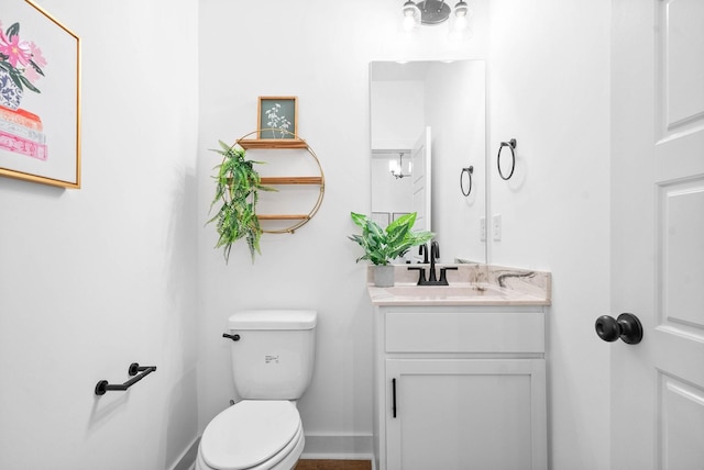 bathroom featuring toilet, vanity, and baseboards