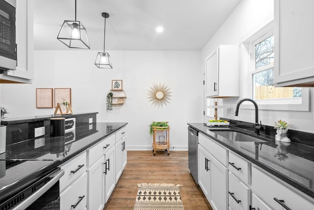 kitchen featuring a sink, stainless steel appliances, wood finished floors, and white cabinetry