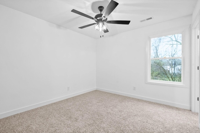 carpeted empty room with visible vents, baseboards, and a ceiling fan