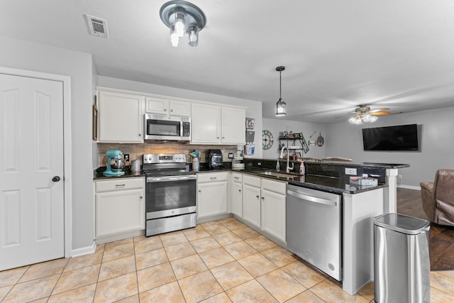 kitchen with visible vents, a peninsula, a sink, appliances with stainless steel finishes, and open floor plan