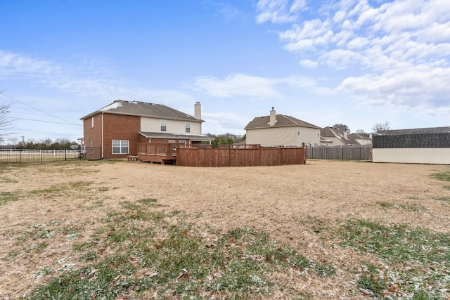 view of yard featuring a wooden deck, a fenced backyard, a storage shed, and an outdoor structure