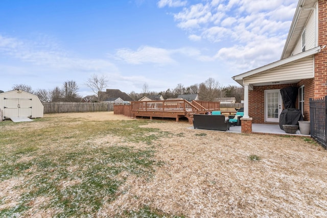 view of yard featuring a deck, a fenced backyard, a shed, an outdoor structure, and an outdoor hangout area