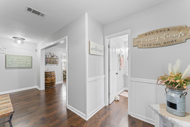 hall with visible vents, dark wood-type flooring, and baseboards