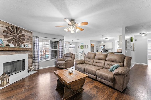 living area featuring dark wood finished floors, a textured ceiling, baseboards, and a high end fireplace