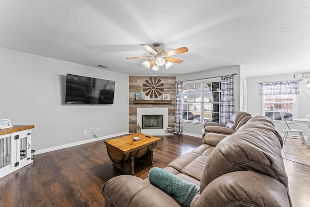 living room featuring visible vents, a ceiling fan, wood finished floors, a fireplace, and baseboards