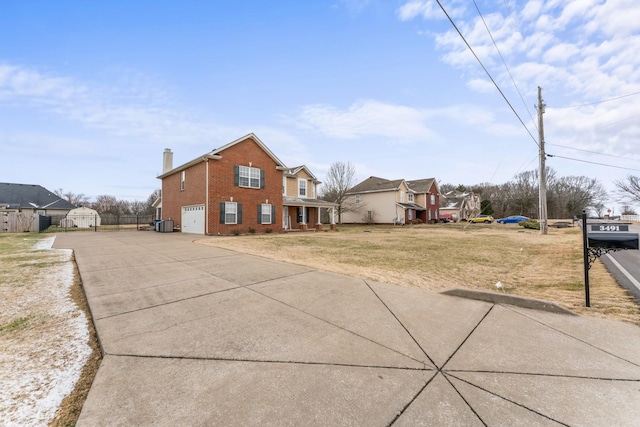 exterior space featuring fence, driveway, a yard, a chimney, and brick siding