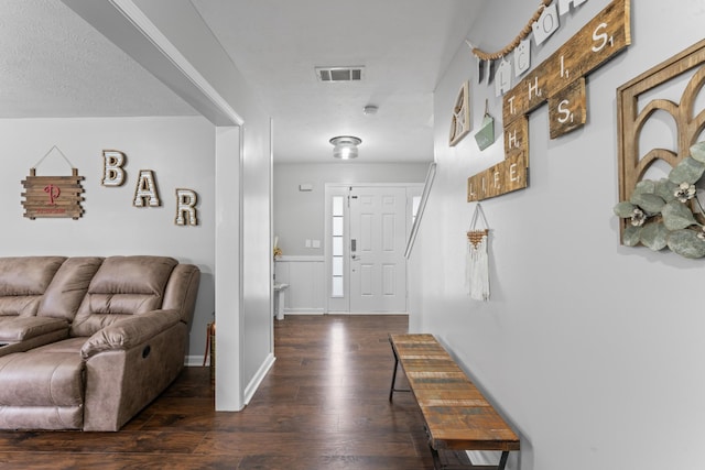 entryway featuring a wainscoted wall, dark wood-style floors, and visible vents