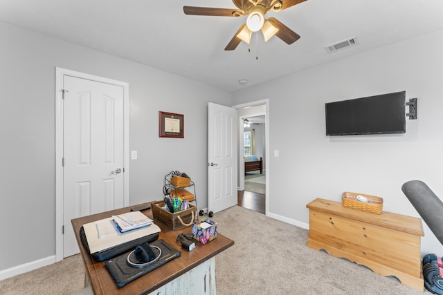 office with visible vents, light carpet, baseboards, and a ceiling fan