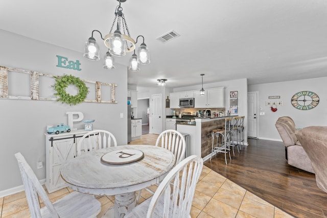 dining area with light tile patterned floors, visible vents, baseboards, and an inviting chandelier