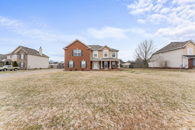 view of front of house featuring a front lawn, fence, covered porch, and brick siding