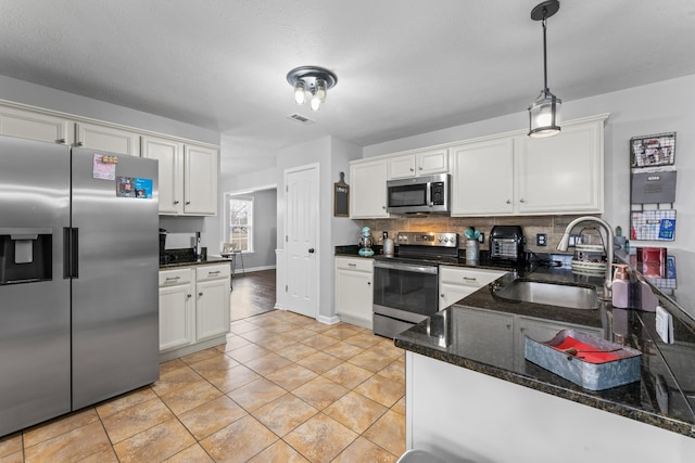 kitchen with a sink, white cabinets, visible vents, and stainless steel appliances