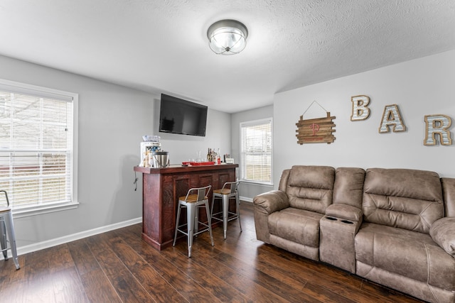 living area featuring a dry bar, a textured ceiling, baseboards, and wood-type flooring