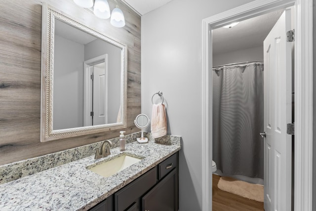 full bathroom with toilet, vanity, and wood finished floors