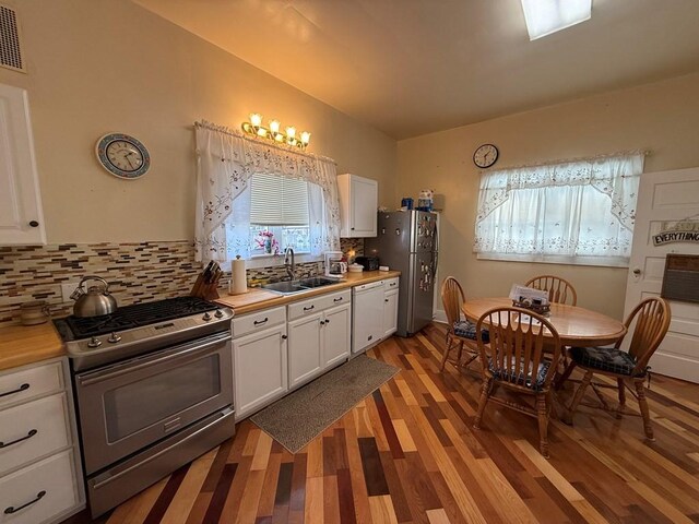 kitchen featuring white cabinets, appliances with stainless steel finishes, light countertops, and a sink