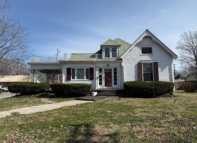 view of front facade featuring a front lawn, a balcony, and metal roof