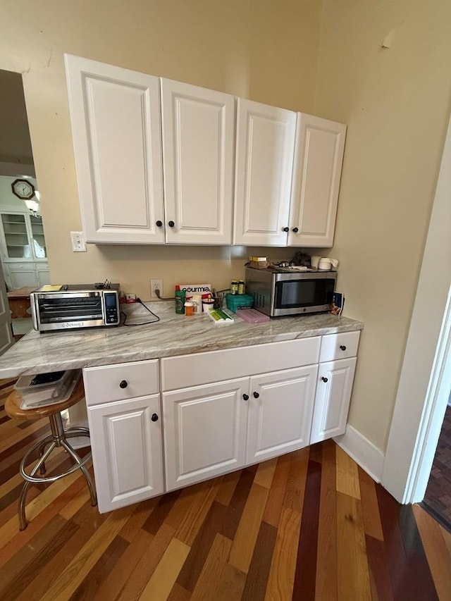 kitchen featuring a toaster, stainless steel microwave, white cabinetry, and light countertops