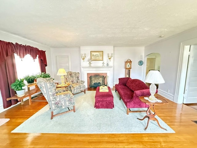 living room featuring a fireplace, a textured ceiling, baseboards, and wood finished floors