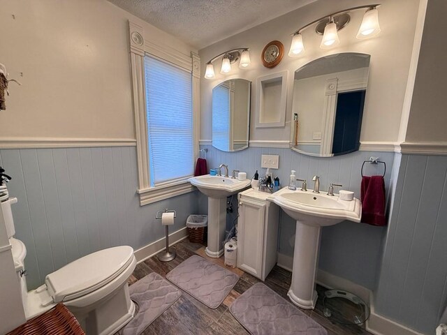 bathroom featuring a wainscoted wall, a textured ceiling, wood finished floors, and toilet