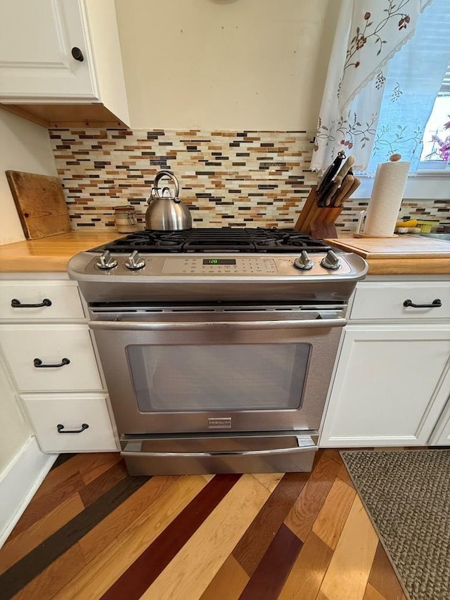 kitchen featuring tasteful backsplash, white cabinets, light wood finished floors, stainless steel range with gas stovetop, and light countertops