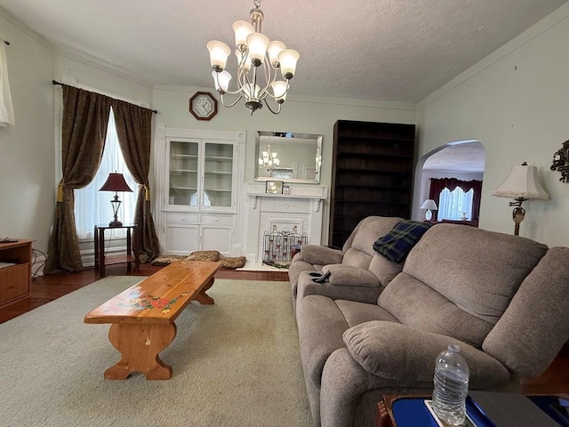 living area with a fireplace, ornamental molding, wood finished floors, and a textured ceiling