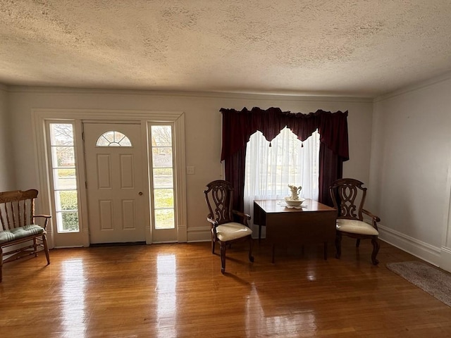 entryway featuring baseboards, a textured ceiling, wood finished floors, and crown molding