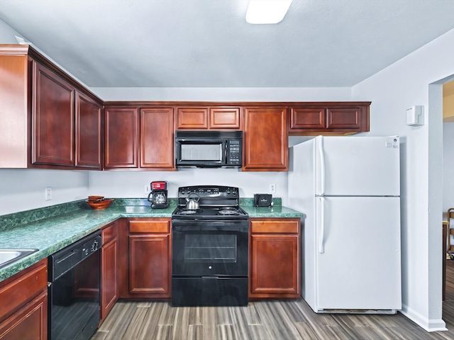 kitchen featuring dark countertops, reddish brown cabinets, wood finished floors, black appliances, and a sink