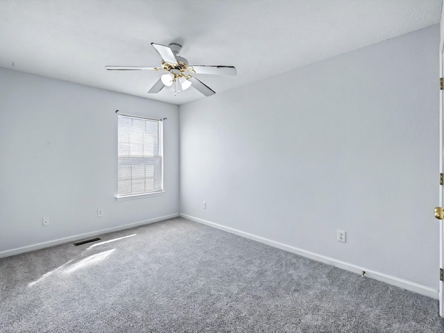 spare room with visible vents, carpet floors, baseboards, and a ceiling fan