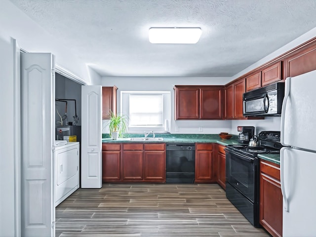 kitchen featuring washer / dryer, dark brown cabinets, black appliances, and a sink