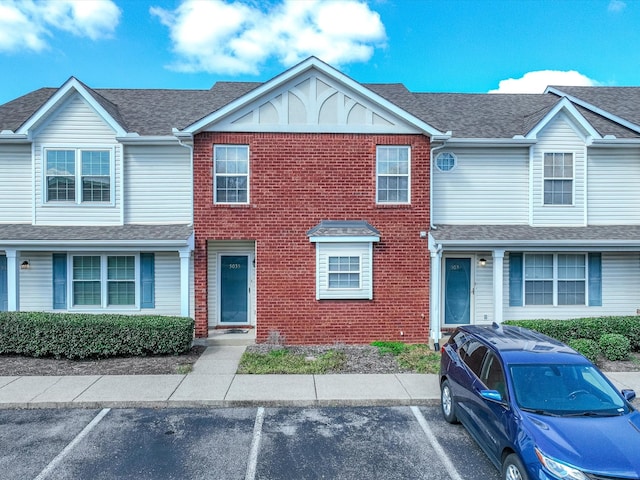 multi unit property with uncovered parking, brick siding, and a shingled roof