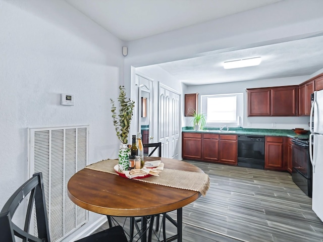 kitchen with black appliances, light wood-style flooring, reddish brown cabinets, and a sink