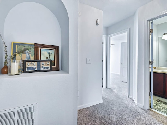 corridor with visible vents, baseboards, and carpet flooring