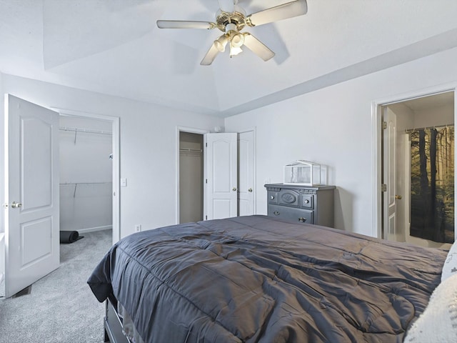 bedroom featuring a ceiling fan, lofted ceiling, multiple closets, carpet flooring, and connected bathroom